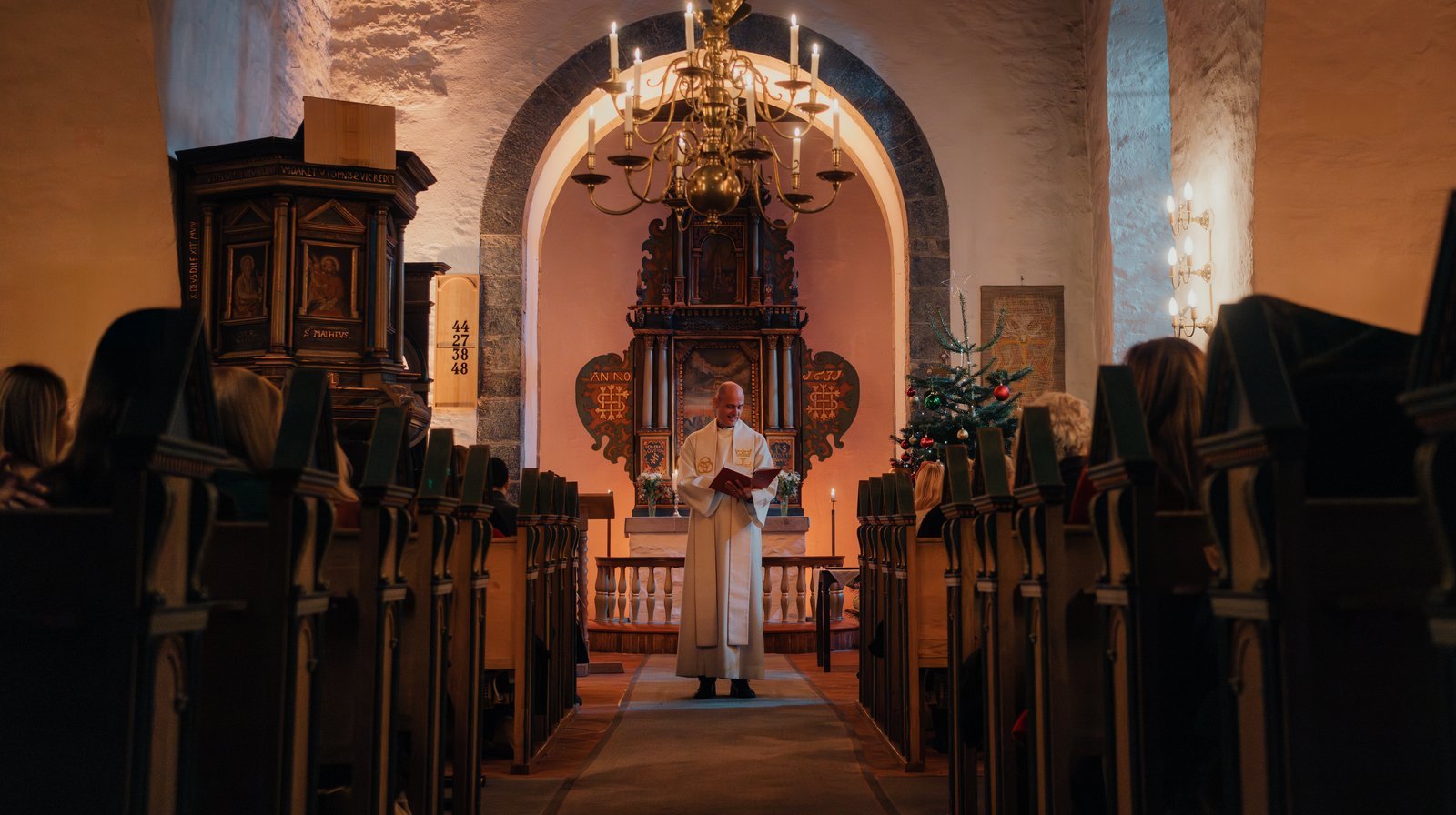 Hvordan vet jeg når jeg skal stå eller sitte, er noe mange lurer på. Det enkle svaret er at presten viser tydelig tegn når det er tid for å stå eller sitte.  (Foto: Willy / Den norske kirke).