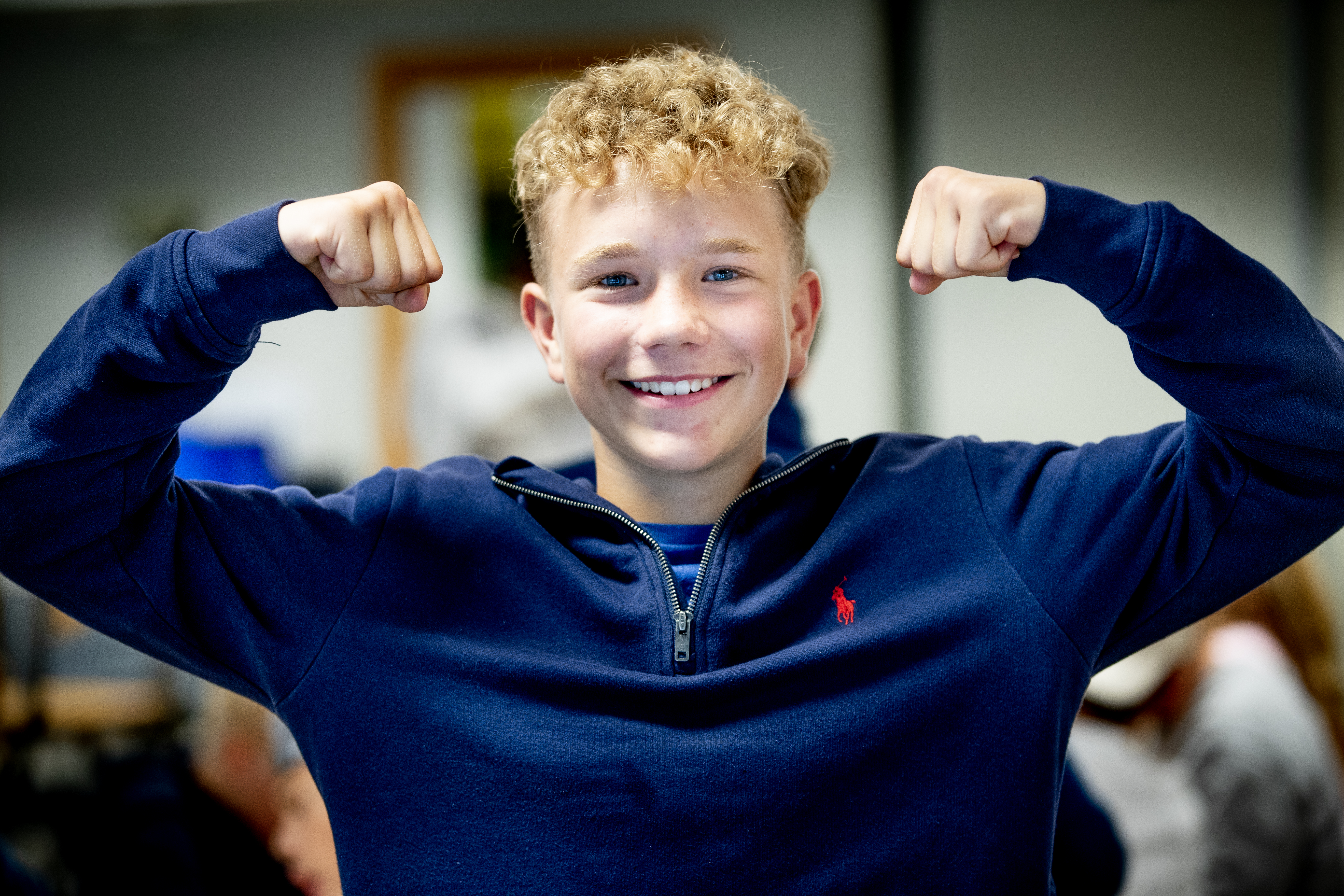 Gutt som smiler med hendene i været