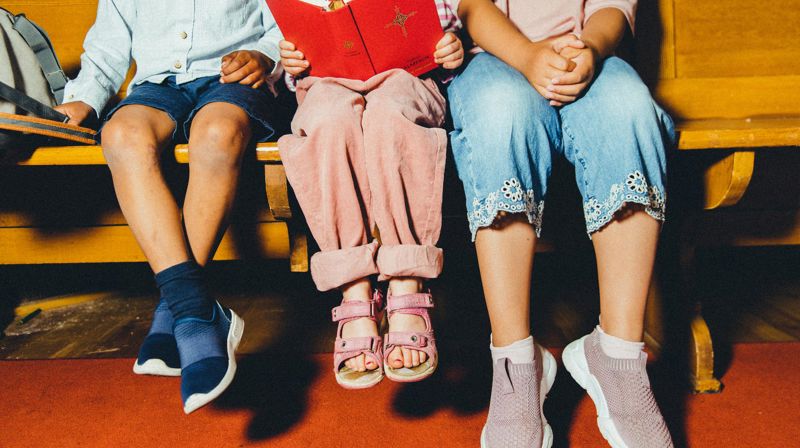 Foto Den norske kirke / Jonathan Vivaas Kise. Bilde av barn i kirka som leser salmebok sammen.