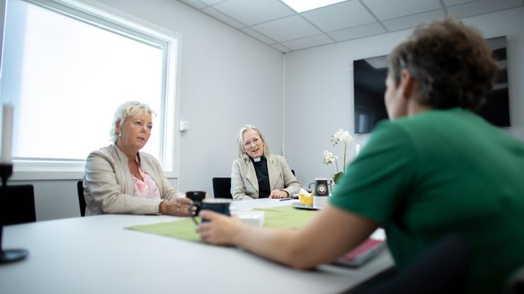 Tre personer rundt et bord der de diskuterer