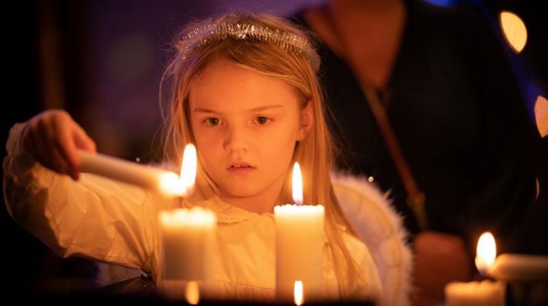 Ei jente utkledd som engel tenner lys.