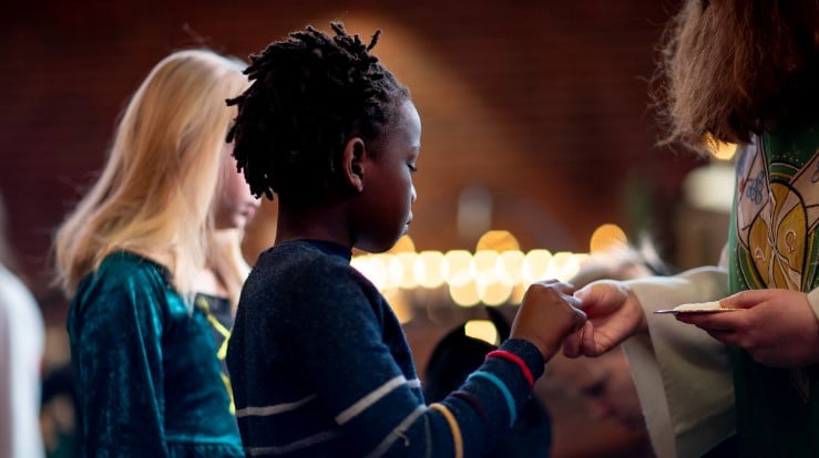 Et barn som mottar nattverd fra presten