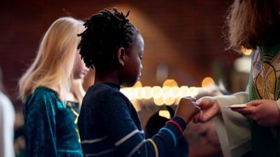 Et barn som mottar nattverd fra presten