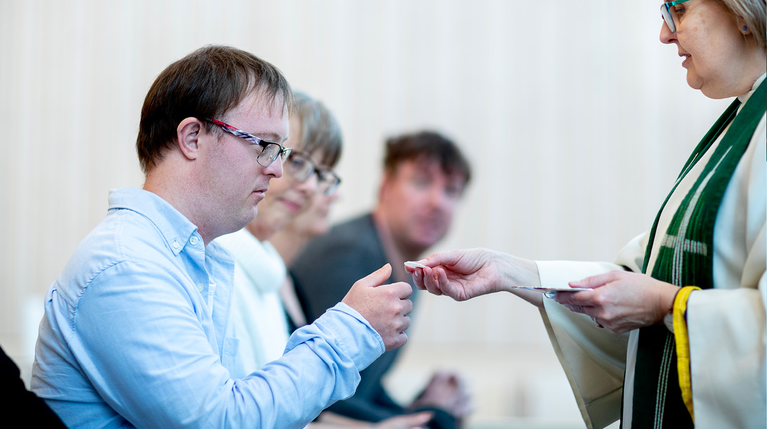 En mann tar imot et oblat under nattverden. Mannen kneler foran alteret. 