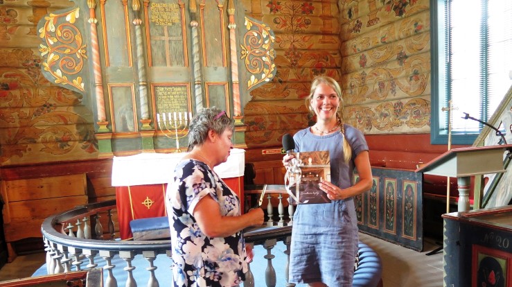 Kyrkjeverje Ingunn Birkeland med den nye boka om Grindheim kyrkje. Til venstre leiar i soknerådet, Vigdis Finseth. Foto: Dag A. Kvarstein