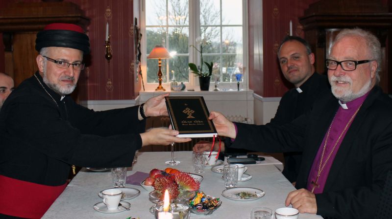 Den assyriske biskopen Mar Odisho Oraham overrekker en bibel på arameisk til biskop Atle Sommerfeldt.