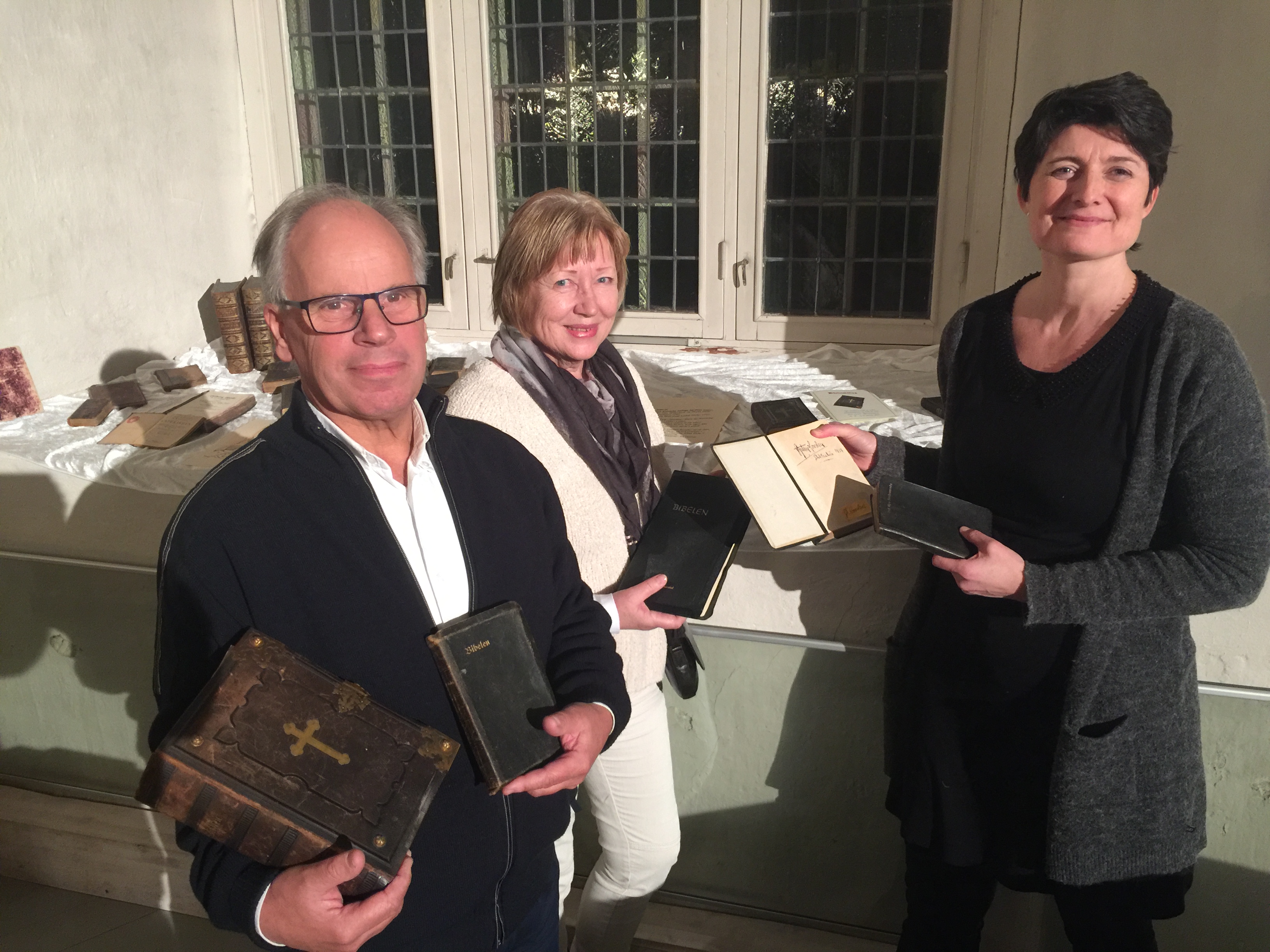 Det ble lånt inn bibler og salmebøker til utstillingen. Her viser Stein Westgaard og Jenny Åsbakk fram gamle bibler i familienes eie. Sokneprest Irmelin Grimstad Bonden til høyre på bildet. Foto: Berit Kristin Klevmoen
