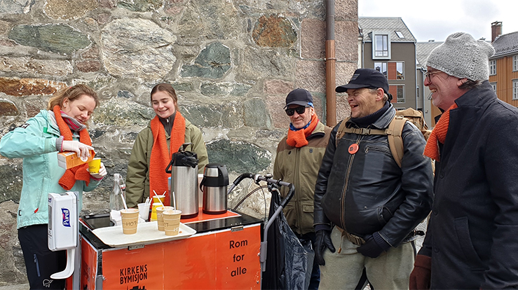 Kirkens bymisjon på plass med kaffevogna utenfor Vår Frue kirke. Til venstre på bildet er Ingrid Bøe og Julie Sandvik, to studenter i Trondheim som har meldt seg som frivillig til å servere kaffe. (Foto: Herborg Finnset)