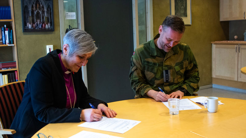 Biskop Herborg Finnset og oberst Ole Marius Tørrisplass signerer samarbeidsavtalen. Den første i sitt slag.
