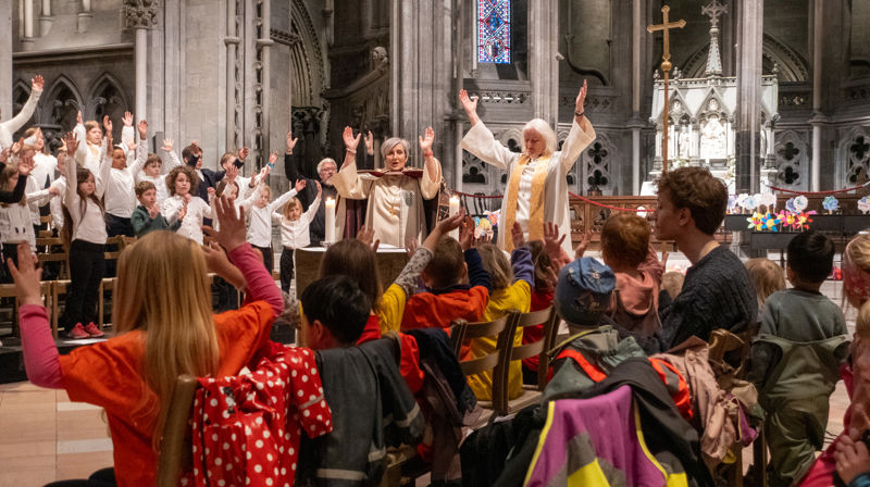 Biskop Herborg Finnset og kapellan Marie Farstad ledet an i salmen «Måne og sol» under den første av tre barnehagegudstjenester i Nidarosdomen denne dagen. I bakgrunnen står aspirantene fra Nidarosdomens guttekor og jentekor (Foto: Magne Vik Ravndal)