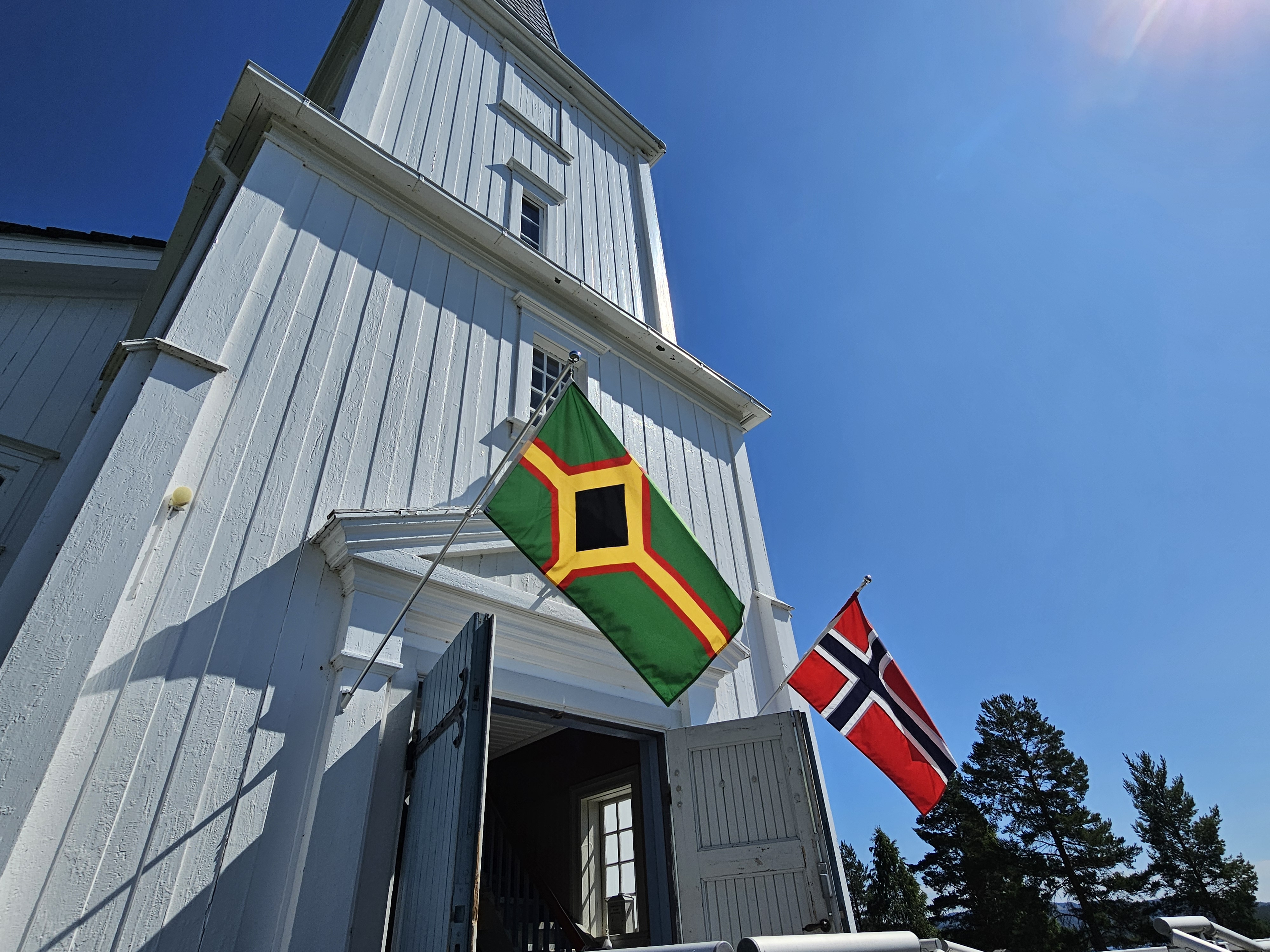 Åsnes Finnskog kirke med skogfinsk og norsk flagg. Foto: Anne Bråten Edvardsen.