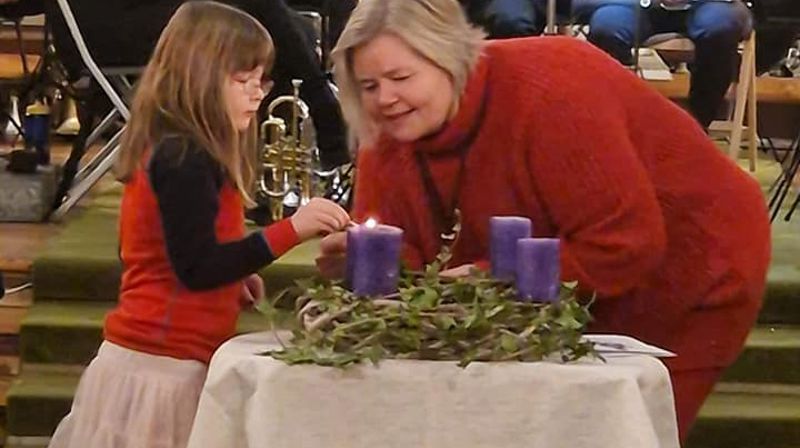 Kyrkjevergje Monica Finden og barn tenner adventskransen