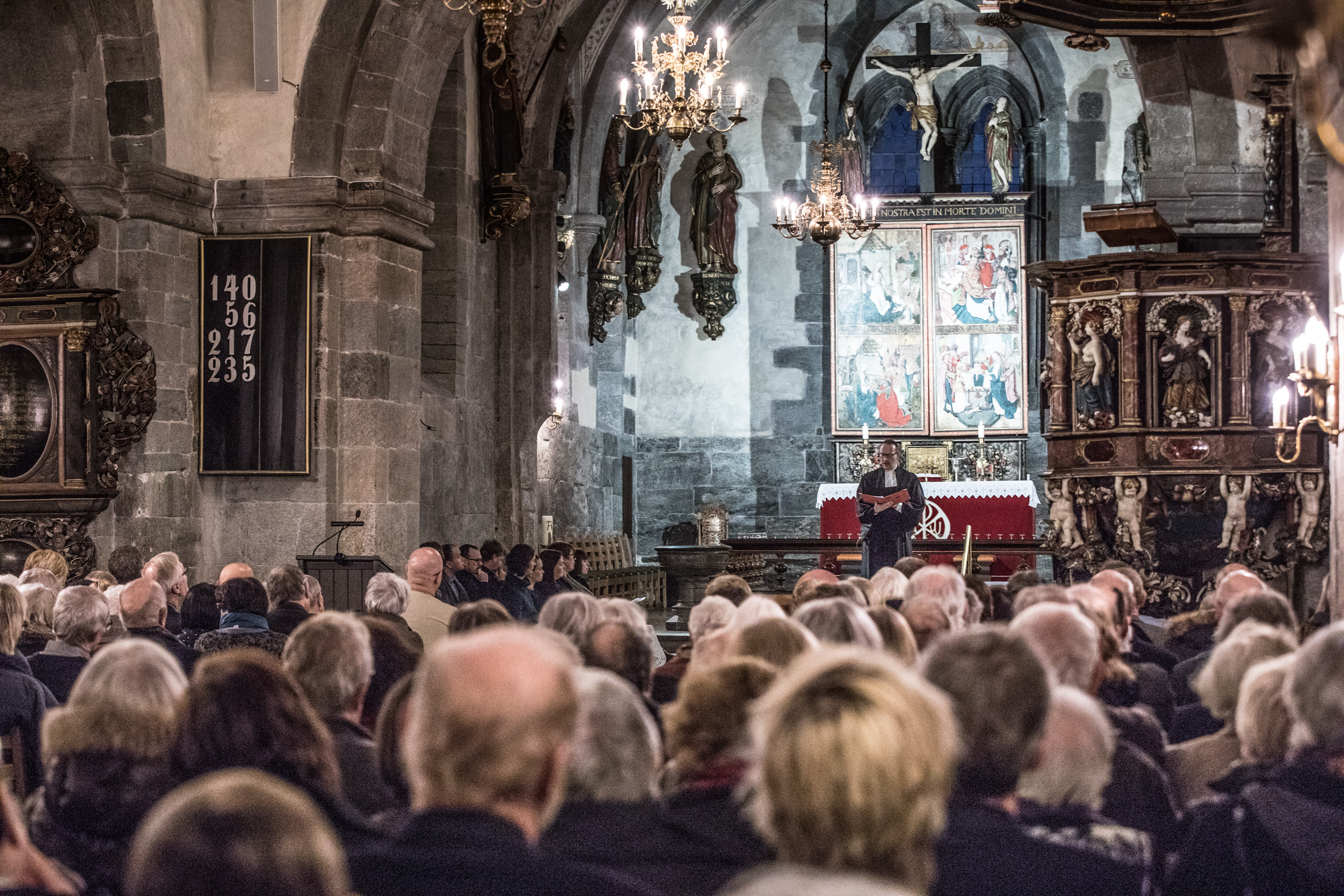 Bilde av menigheten ved gudstjeneste i Mariakirken. Sett fra bak i kirkerommet.