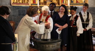 Dåpsfølge og prest ved døpefonten i Marakirken.