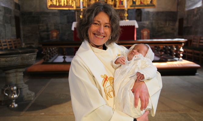 Prest Hildegunn Isaksen som holder dåpsbarn i Mariakirken.