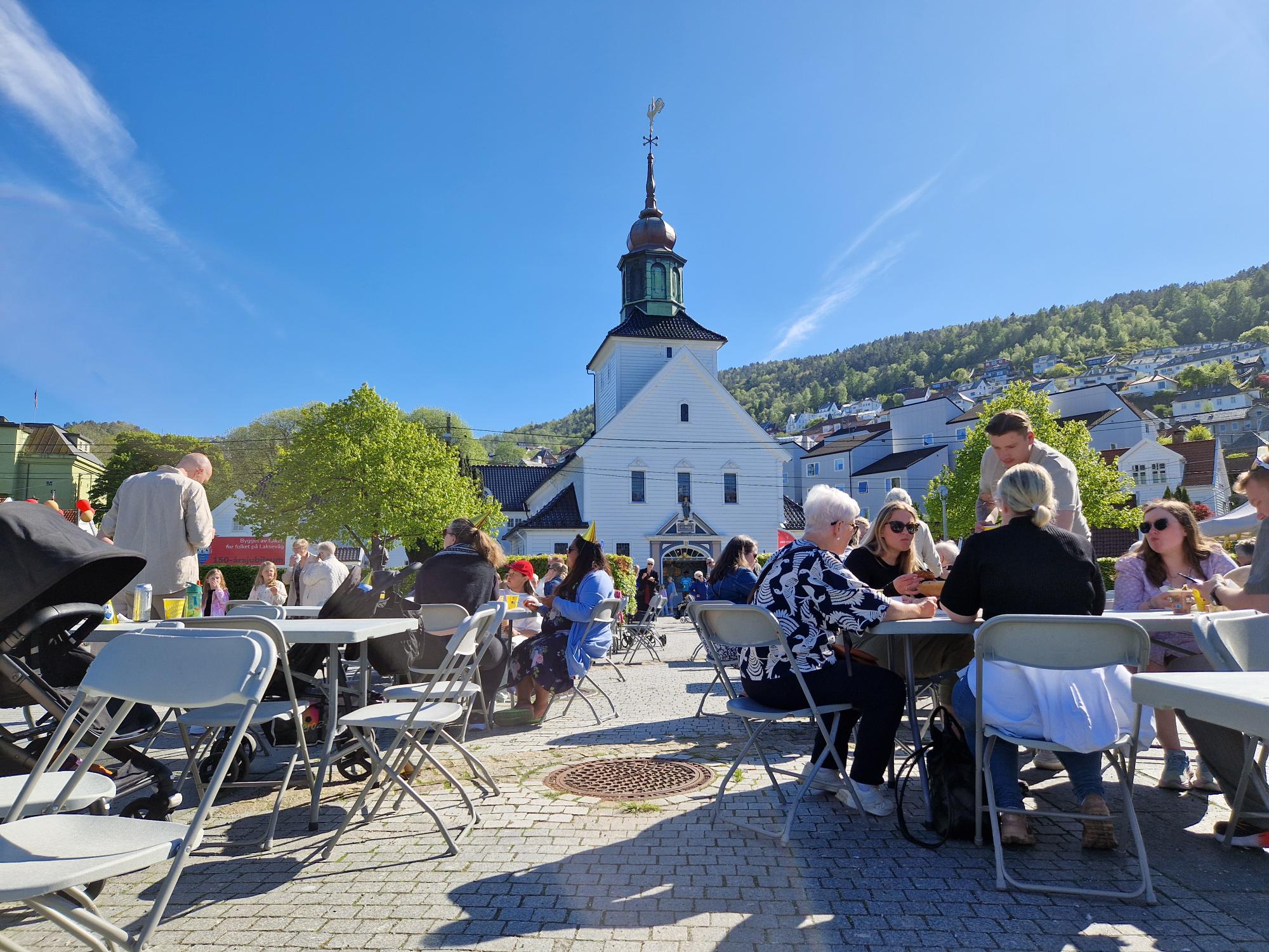 Kirkebukten foran Laksevåg kirke, badet i sol og full av glade mennesker.