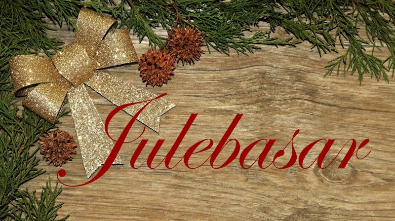 Julepynt (gullsløyfe, sedertregreiner) på grove treplankar og påskrift «Julebasar» med raud skjønnskrift