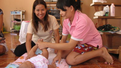En nybakt mamma steller babyen sin sammen med en ansatt ved Nådehjemmet, som ser på kameraet og smiler.