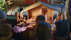 Barnehagebarn legger fra seg sine fint dekorerte stjerner foran julekrybba i Bakkebø kirke.