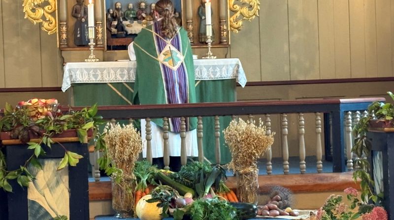 Sokneprest Eli-Kristin Sjøli Ulsund i Nes kirke, pyntet til høsttakkefest. Foto: Inger Stensrud Haug 2025.