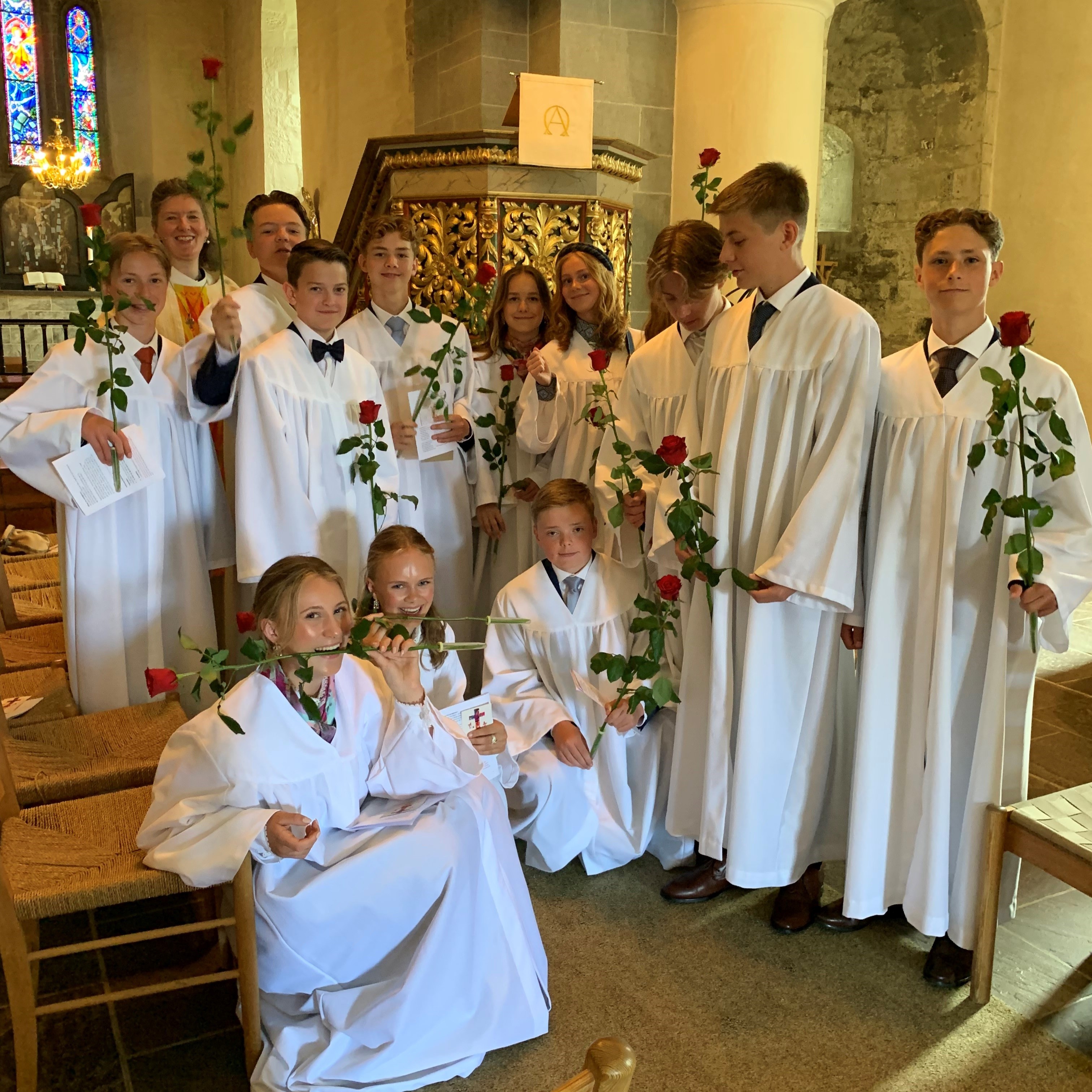 Konfirmantene får ofte overrakt en rose under konfirmasjonsgudstjenesten. Her er fjorårets konfirmanter i Nikolaikirken sammen med roser og sokneprest Therese Wagle Bazard (foto Kari Røken Alm). 