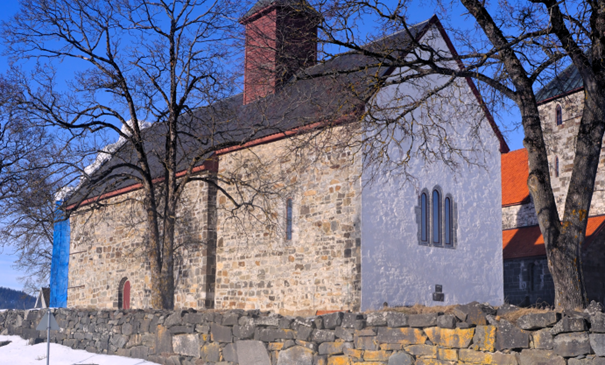 Mariakirken med hvitkalket østvegg og stillas på vestveggen. Nå er østveggen hvitkalket og stillaset satt opp mot sør for å ta siste veggen. I høst vil all sement i fugene være fjernet og erstattet med kalk og kirken være hvitkalket på nytt (foto: Morten Stige). 