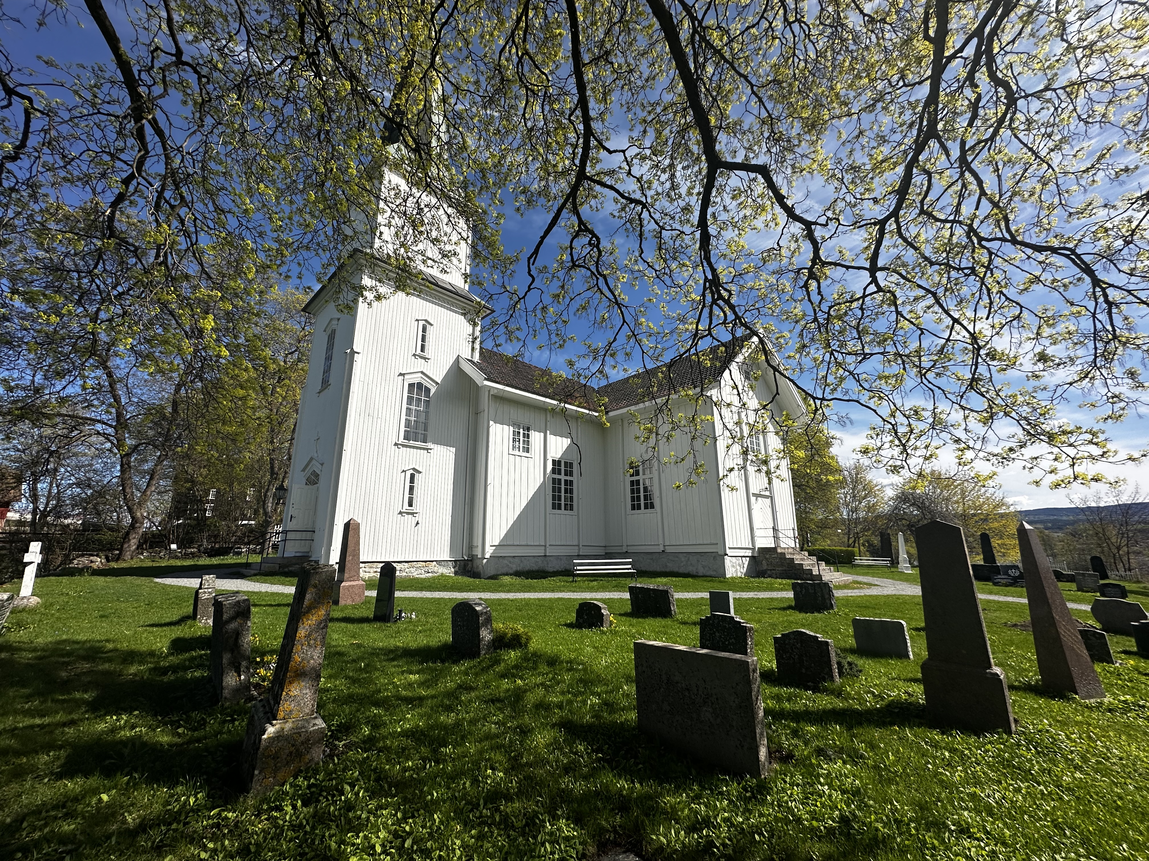 Nes kirke i klar vårsol og grønt (foto: Eli-Kristin Sjøli Ulsund). 