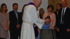 Familie og faddere står rundt mens Jorunn bøyer seg over døpefonten.