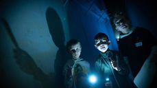 Tre gutter står i mørket. To av dem har forstørrelsesglass, og lommelykt som lyser. Foto: Sven-Erling Brusletto