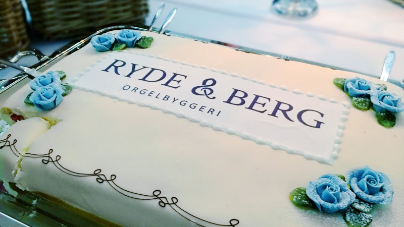 Bløtkake pyntet med roser og logoen til orgelbyggeriet Ryde & Berg.