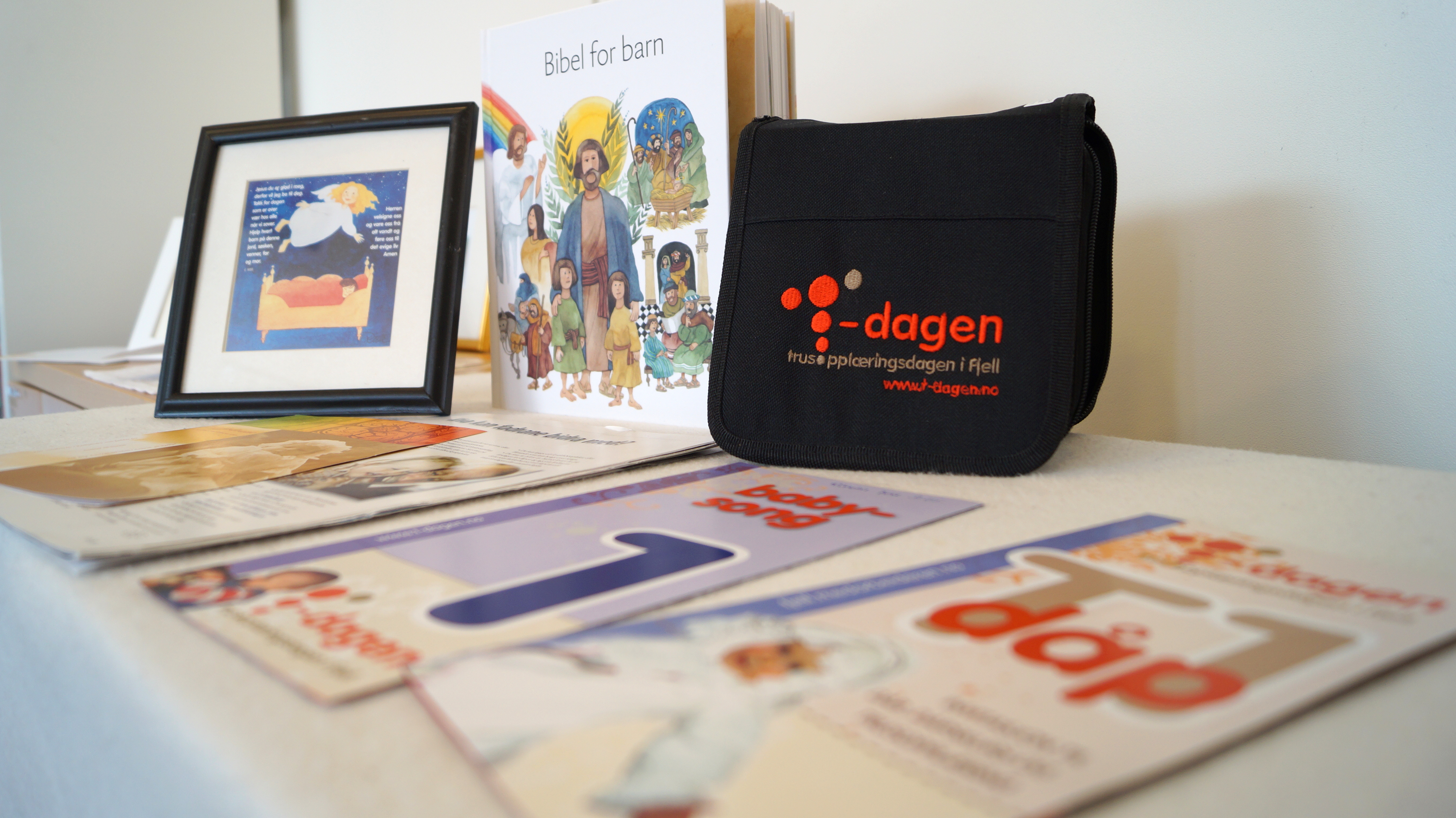 Brosjyrer, bibel og trosopplæringsmateriale plassert på et bord. 