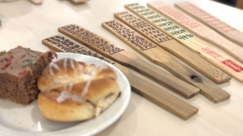 Et kakestykke og en bolle på et lite fat, ved siden av ligger syv årer som brukes til basar