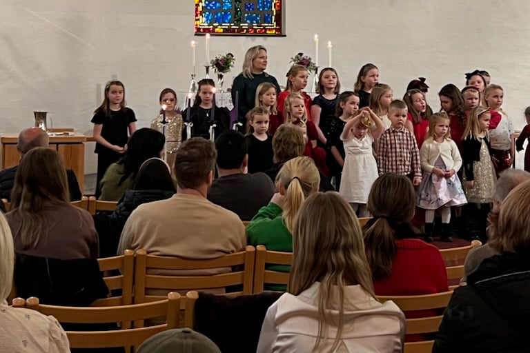 Et barnekor st&aring;r framme i kyrkja og syng til publikum