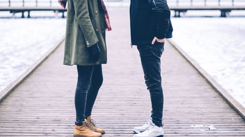 En dame og en mann står mot hverandre på en brygge, de går med jakker.