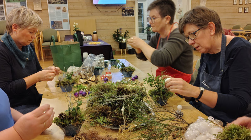 Fire damer sitter rundt et bord og lager kranser