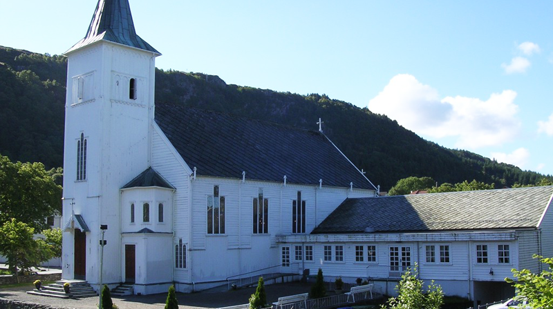 Fjell kyrkje i sollys. Ein kan sjå at kyrkja er slitt i malinga.