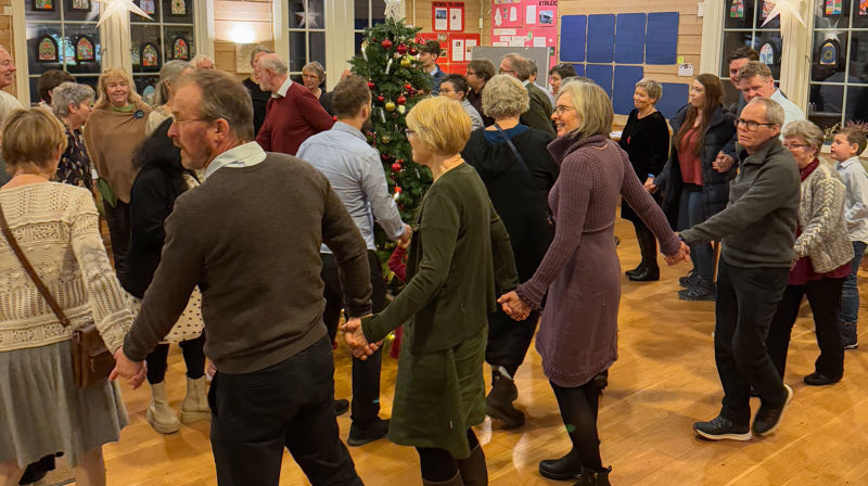 Mennesker går i sirkel rundt juletreet og syng