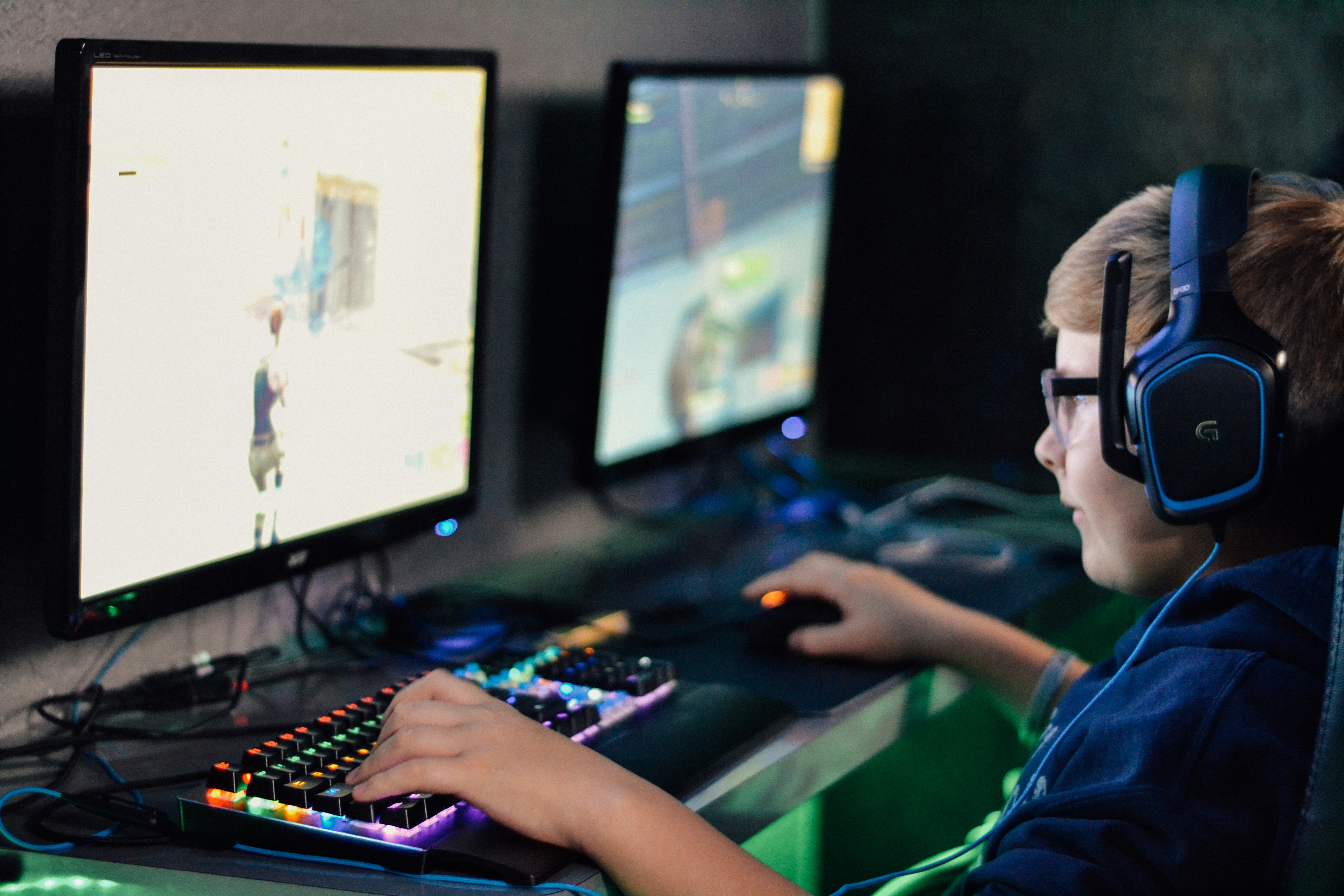 En ungdomsgutt sitter ved en data og gamer, han har headset på hodet