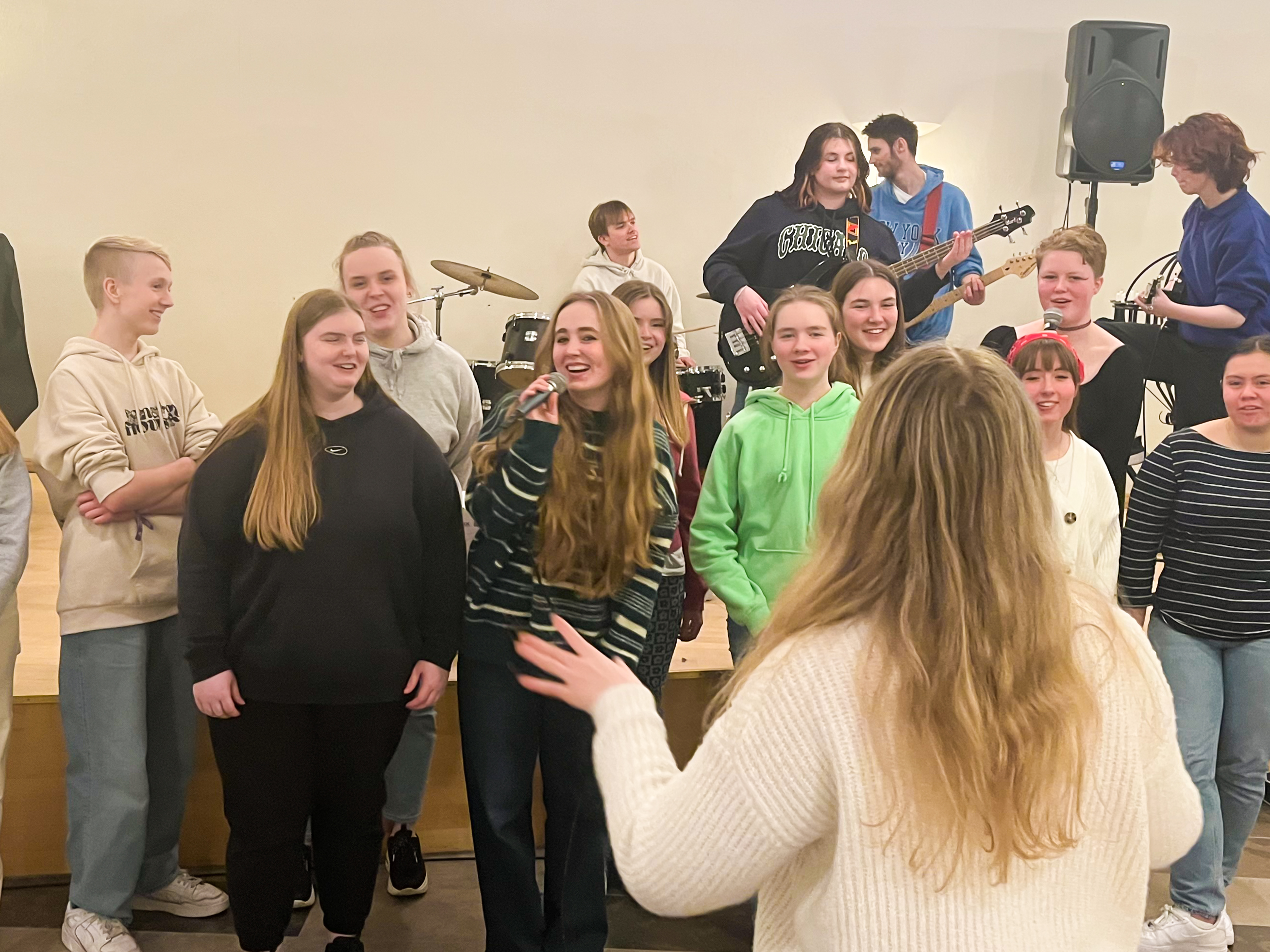 Ungdommer som synger i kor, med et band i bakgrunnen
