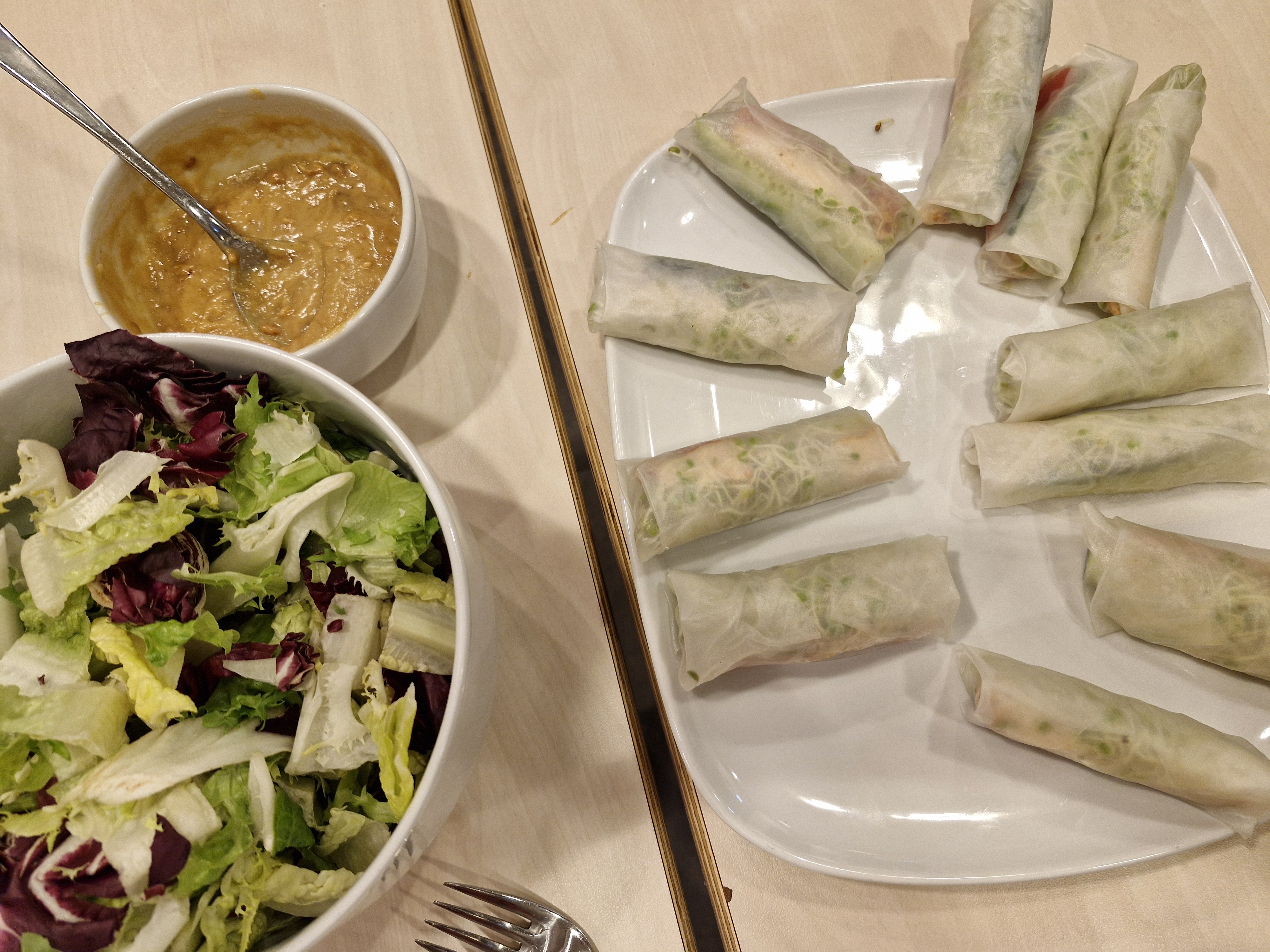 Til høyre er eit fat med vårruller og til venstre ei skål med saus og si skål med salat.