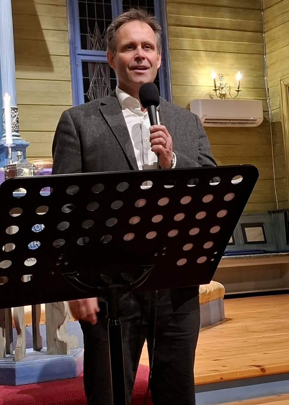 En mann st&aring;r fremme i en kirke og synger i mikrofon