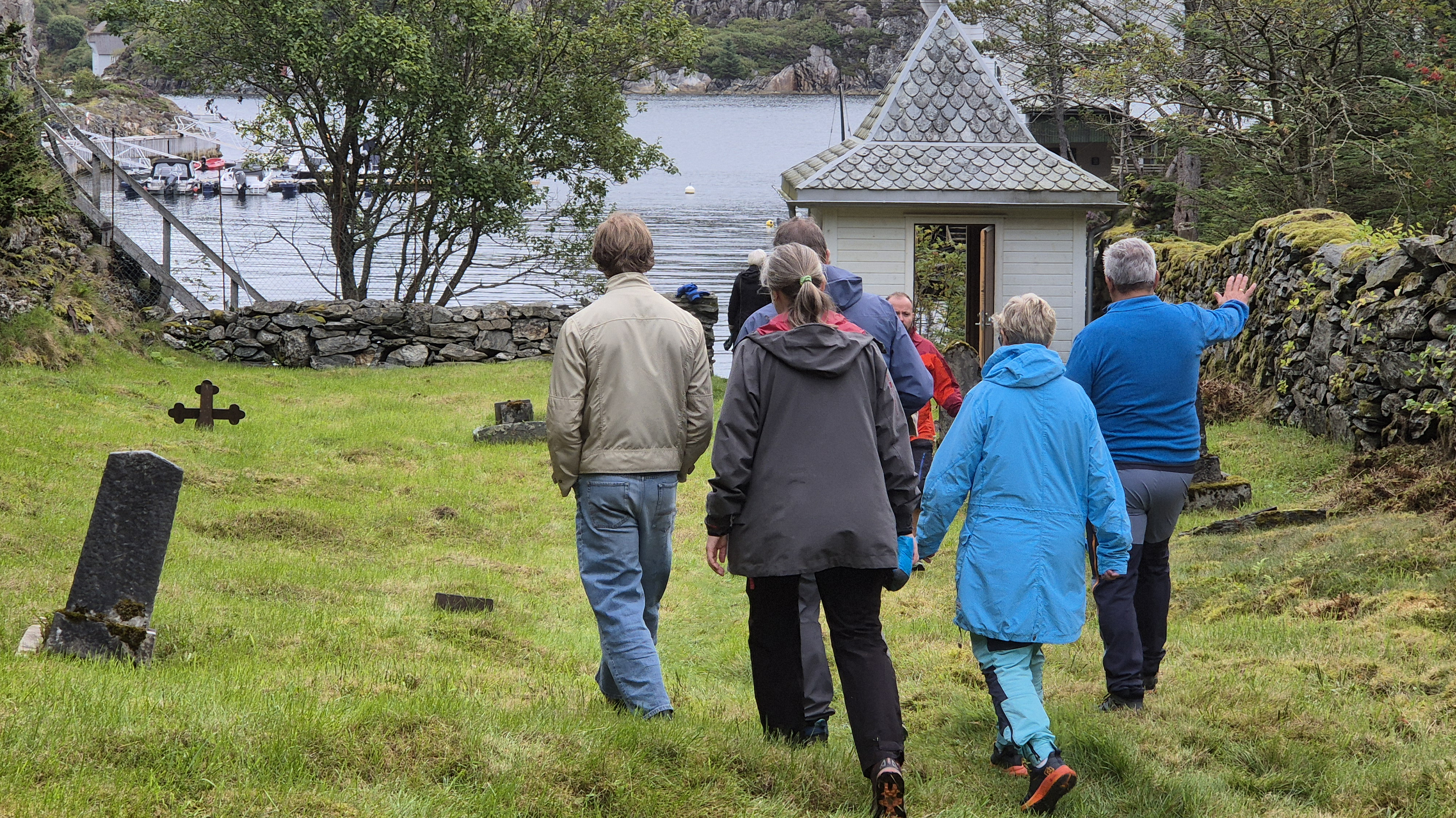 Menneker går på gresset mot sjøen og porten ut av gravplassen