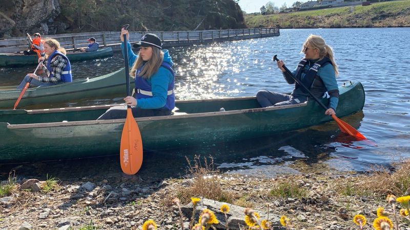 To i kano, på vei inn mot land, det er sol og vår