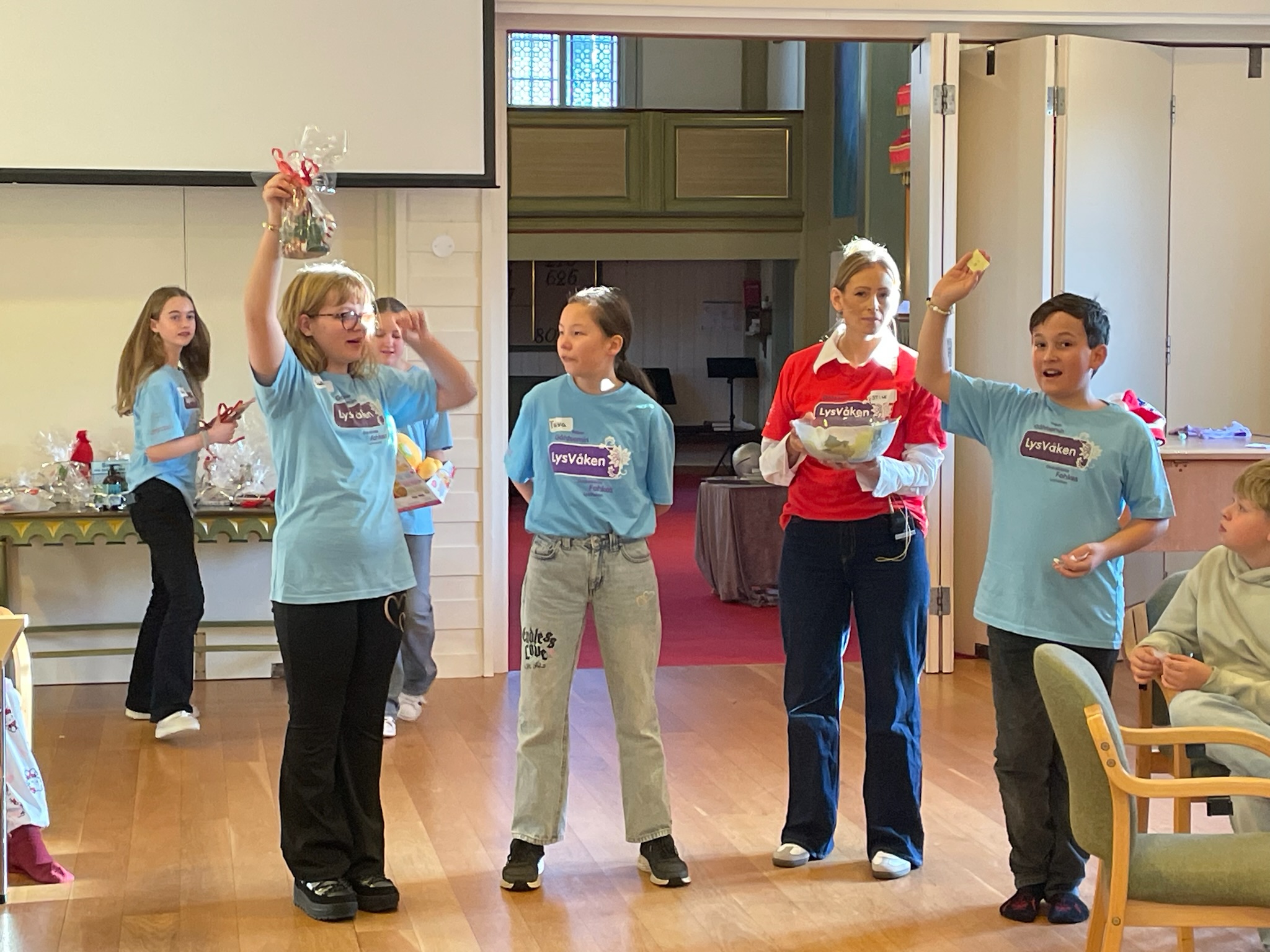 tolvåringar held basar og held opp premie og vinnarlodd