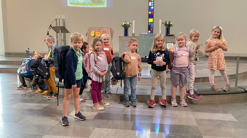 Flere førsteklassinger står fremme i Foldnes kyrke, dei har skulesekken på