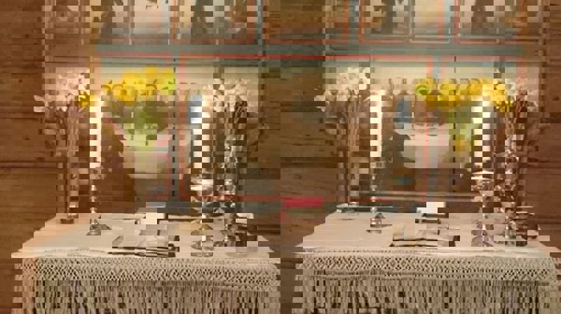 Alteret i Volbu kyrkje pynta med påskeliljer og bordet dekt for Jesu måltid Foto: Eli Vatn