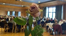 Ei rose med selskap frå jubilantfest 2022 i bakgrunnen