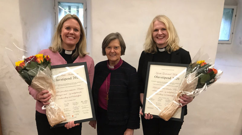 Silje Kivle Andreassen (til venstre) og Kjersti Gautestad Norheim fikk stipend og blomster overrakt av preses Helga Haugland Byfuglien. (Foto: Bispemøtet)