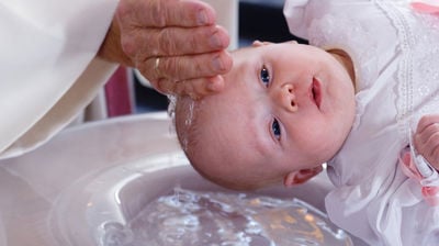 Nærbilde av et dåpsbarn som blir døpt.