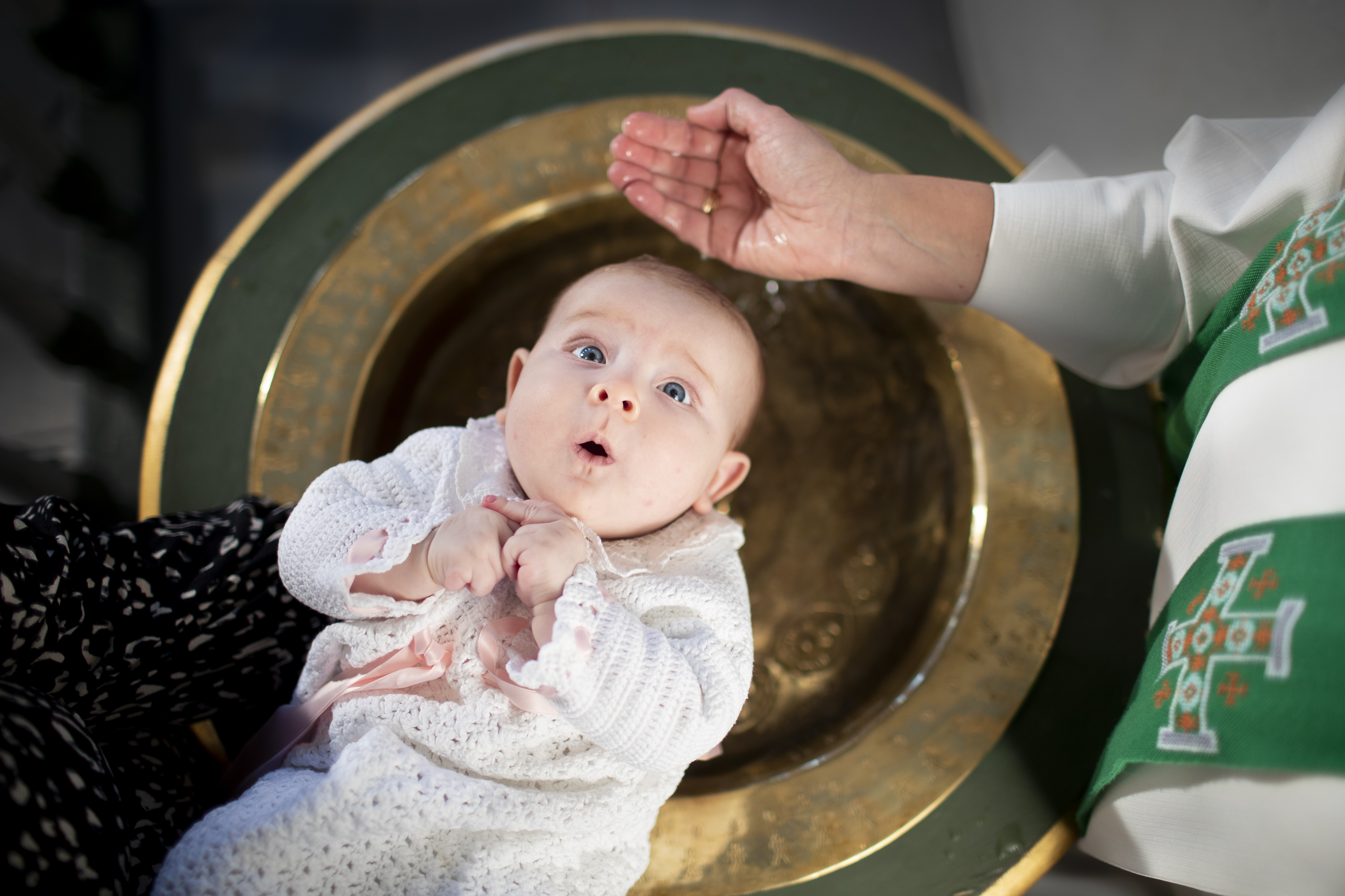 En baby blir døpt i døpefont